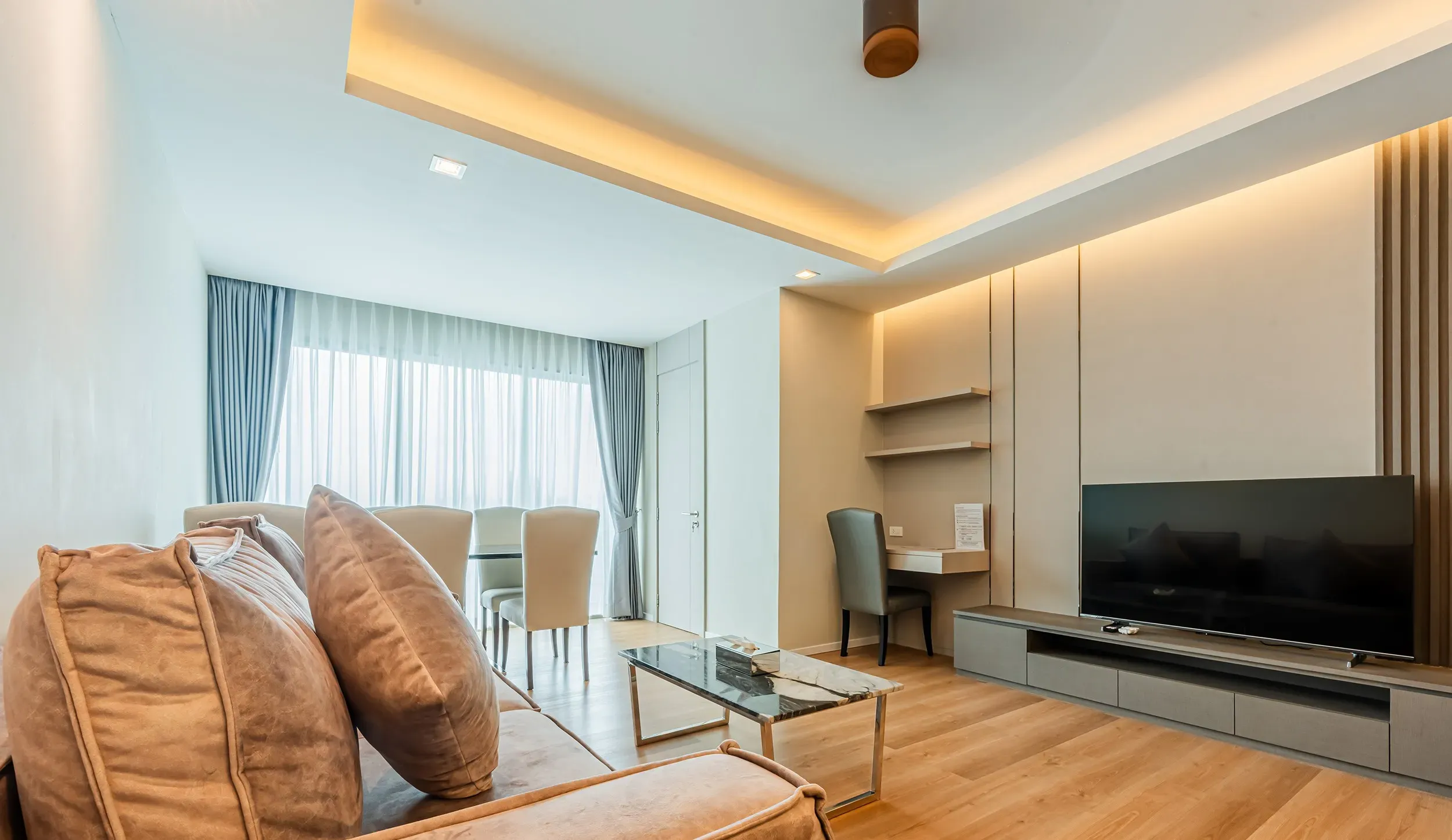Bright living room with a comfortable sofa, flat-screen TV, and dedicated workspace